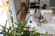 © Sergey Narevskih/Stocksy - Female freelancer sitting on couch using laptop near Christmas tree