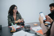 © qunica.com - Young professionals engaging in a creative brainstorming session at an office setting with smart phones and stationery.