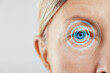 © New Africa - Vision test. Mature woman and digital scheme focused on her eye against white background, closeup