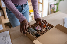 Black worker packing beauty products in box