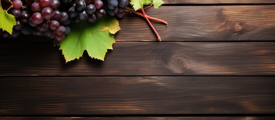 Wall Mural - A cluster of grapes with vine leaves arranged on top of a wooden table, creating a flat lay composition with room for text or other elements.