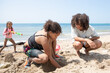 © Anya Brewley Schultheiss/Stocksy - Children digging in the sand as their sister sneaks up on them.