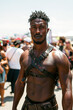 muscular black gay man with bare abs in leather harness at the LGBT pride parade on the street