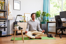 Self-employed man meditating on mat after workday