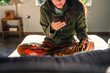 © Luis Herrera/Stocksy - woman with her phone on her living room