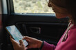 © Luis Herrera/Stocksy - woman traveler in car using phone map