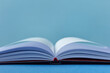 © Yaroslav Danylchenko/Stocksy - Close-up of open notebook on blue background.