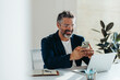 © (JLco) Julia Amaral - Focused professional man smiling at smartphone in bright modern office