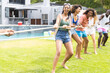 Diverse group of friends enjoy a tug-of-war game on a sunny lawn with copy space