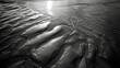 Abstract patterns of light and shadow on a sandy beach.