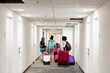 © Anya Brewley Schultheiss/Stocksy - Group of children walking down a hotel hall with their luggage.
