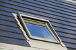 Dachfenster an einem Einfamilienhaus mit Solardachziegeln. Solarziegeln sind eine schöne und hochwertige Alternative zu gängigen Photovoltaikanlagen