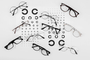 Sticker - Vision test charts and glasses on white background, flat lay