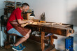 © Ezequiel Giménez/Stocksy - Woodworker planning part of violin with plane