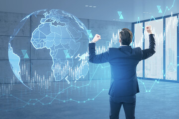 Fototapete - Back view of young businessman celebrating success with creative globe hologram with growing forex chart on blurry office interior background. Global business, international stock market concept.