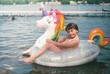 © Serena Burroughs/Stocksy - happy girl with a unicorn floaty at the lake in summer