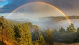 Fototapeta Tęcza - rainbow over the river near the misty forest 