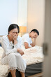 © bongkarn - An unhappy, sad Asian wife is sitting on the bed and crying after an argument with her husband.