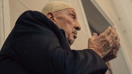 Wall Mural - Old Muslim man with a prayer cap praying to Allah at Mosque in Ramadan month