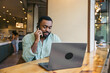 © Pedro Merino/Stocksy - A man on a phone call while using laptop in a cafe