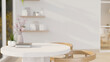 © bongkarn - A close-up shot of a round white table with wooden armchairs in a beautiful minimalist living room.