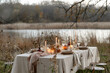 Outdoor table setting in in style of beige colors with linen tablecloth, napkins and decorated with candles. Autumn mood.