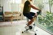 © DragonImages - Man riding exercise bike at home in the morning