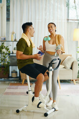 Wall Mural - Sporty couple drinking water and chatting after working out together at home