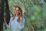 Fototapeta Tulipany - Wiosenny portret młodej ładnej kobiety w kapeluszu, w parku , wśród drzew.