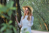 Fototapeta Tulipany - Wiosenny portret młodej ładnej kobiety w kapeluszu, w parku , wśród drzew.