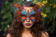 Close-up of a young woman wearing a colorful butterfly mask at a masquerade