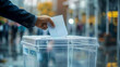 a businessman's hand puts a ballot into a transparent ballot box