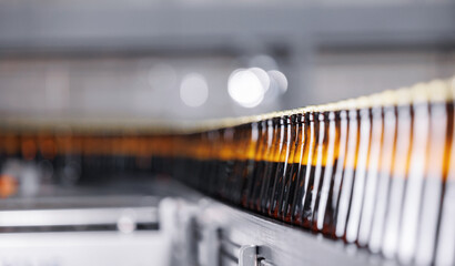 Wall Mural - Brown glass beer bottles on conveyor belt Automated brewery industry manufacturing with sunlight