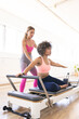 © Wavebreak Media - Young Caucasian woman assists young biracial woman on Pilates reformer