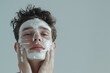 Yung handsome man applies the facial mask to face, Men's beauty and self care advertising background. Copy space