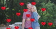 Image of heart balloons over happy caucasian couple in garden