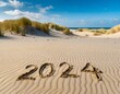 2024 in den Sand am Strand geschrieben mit Dünen im Hintergrund