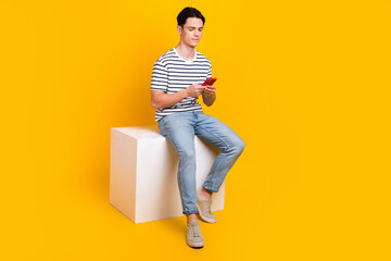 Sticker - Full length photo of good mood cool guy dressed striped t-shirt chatting modern gadget empty space isolated yellow color background