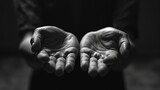 Fototapeta  - Outstretched hands in a plea or offering on a black background. Black and white image of a person's cupped hands in a giving gesture.