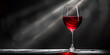 Closeup wine glass filled with red wine on dark gray wall background with sun rays on it 