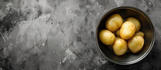 Wall Mural - A metal bowl containing peeled potatoes is placed on top of a rustic table. The potatoes are neatly arranged and ready for cooking.