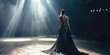 A solitary model in a luxurious black dress stands on a dimly lit runway with dramatic spotlights.