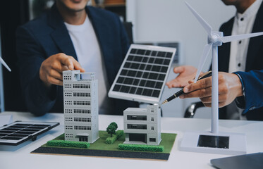 Two Young Engineers Expertise in Solar Cell Installation Meetings and Discussion in The Job. Planning to Install Solar Photovoltaic Panels on Roof Top in The Office Room with Factory Building Plan.