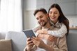 © Prostock-studio - Happy couple enjoying time with digital tablet on couch
