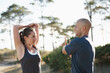 © Katie/peopleimages.com - Nature, stretching and couple in forest for fitness, workout and commitment to healthy body. Exercise, wellness and people in arm muscle warm up for outdoor training, performance and morning in woods