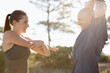© Katie/peopleimages.com - Fitness, trees and couple stretching arms for workout, commitment and healthy body in nature. Exercise, man and happy woman in warm up for training, muscle and morning in woods with personal trainer.