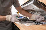 Fototapeta Zachód słońca - Kitchen Appliances Installer Checking For Gas Leaks Using a Detector