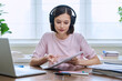 © Valerii Honcharuk - Young female college student in headphones studying using laptop computer for video chat