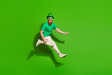 Fototapeta Panele - Full body profile portrait of carefree person jump raise fist rejoice empty space isolated on green color background