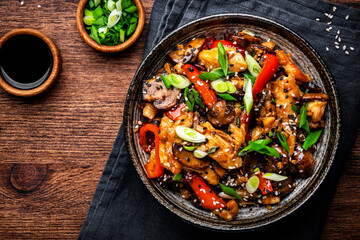 Wall Mural - Stir fry turkey slices with red paprika, mushrooms, chives and sesame seeds with ginger, garlic and soy sauce. Old wooden table background, top view